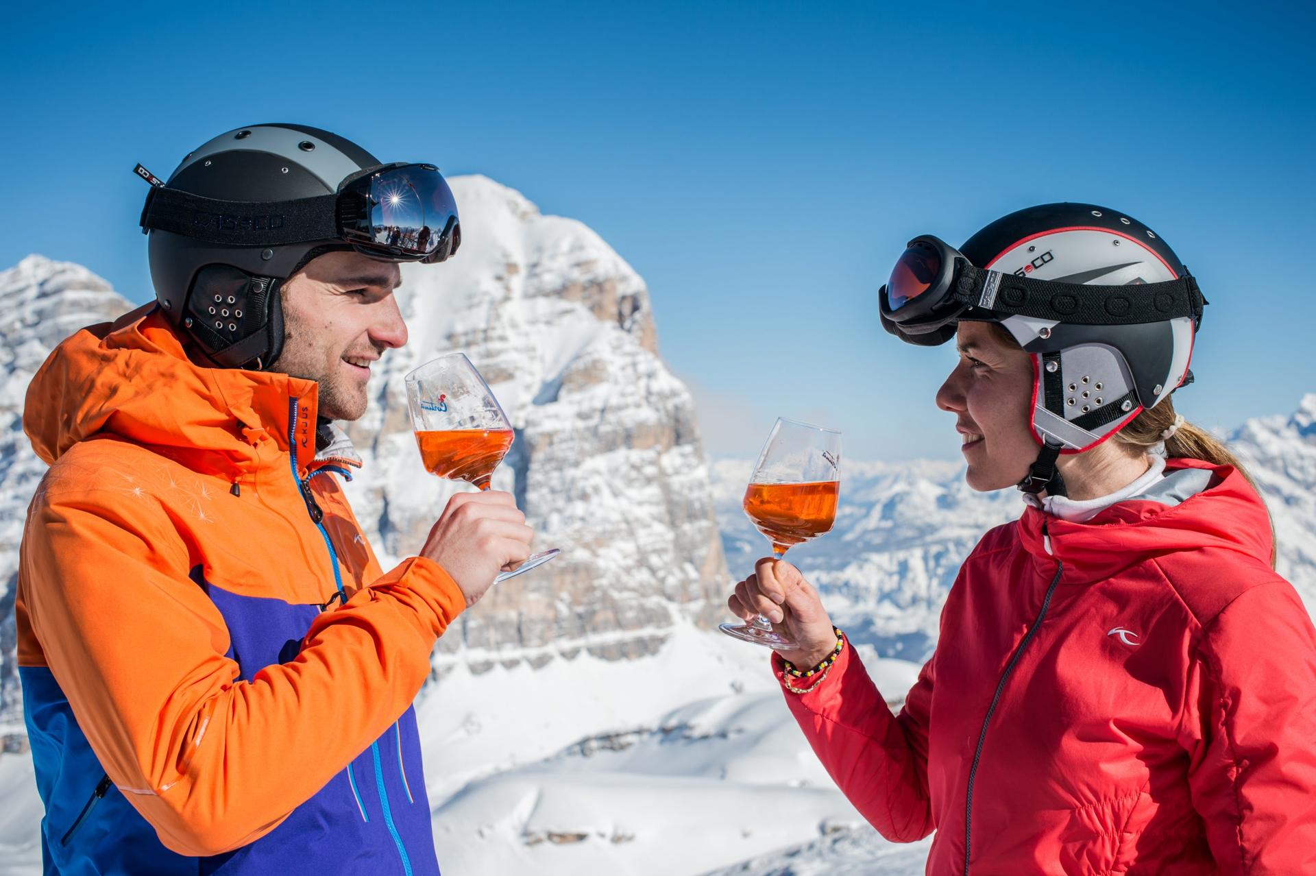 Couple drinking aperol spritz at top of mountain in dolomites